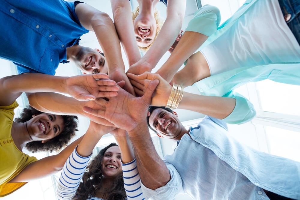 Sales team putting their hands together in circle